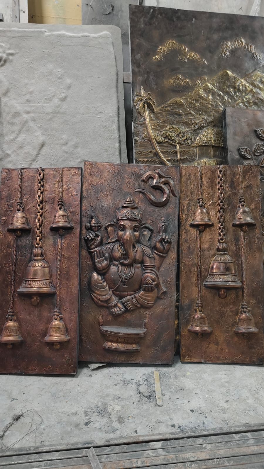 Copper-toned relief panels of Ganesha flanked by hanging temple bells