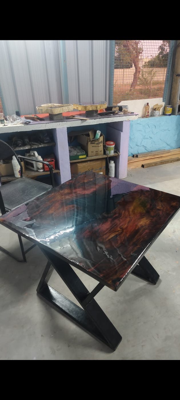 Small side table with a fiery red and gold marbled epoxy resin top on an X-frame metal stand