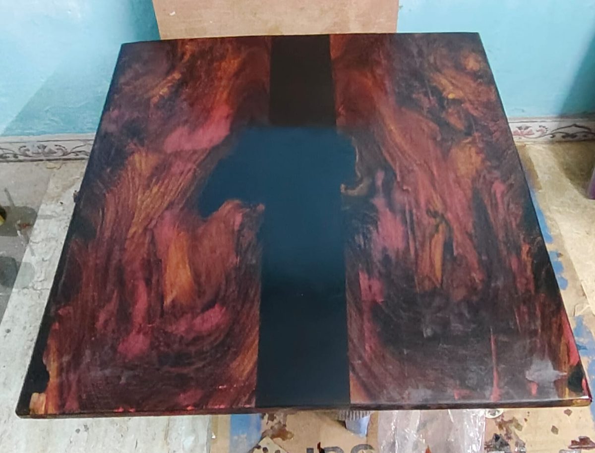 Overhead view of a square tabletop with a lava-style red, orange and black epoxy resin river down the centre